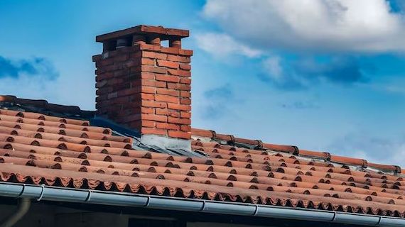 Straight brick chimney above a tiled roofline